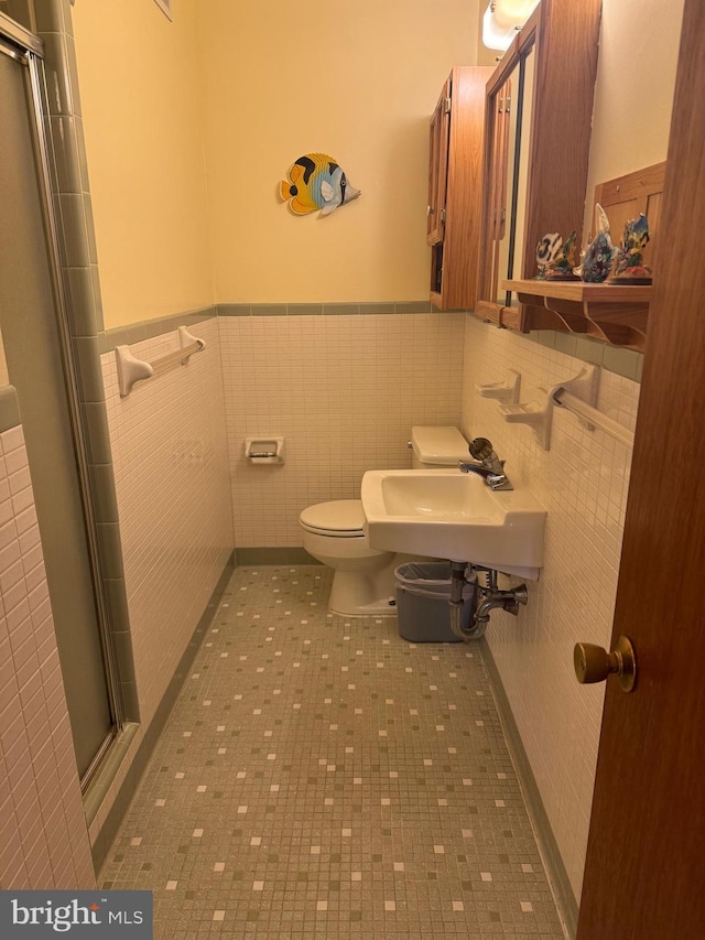 bathroom with sink, tile patterned floors, an enclosed shower, toilet, and tile walls