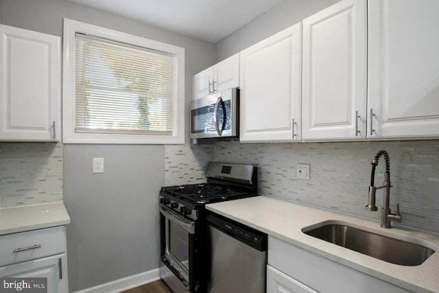 kitchen with tasteful backsplash, appliances with stainless steel finishes, sink, white cabinets, and light stone counters