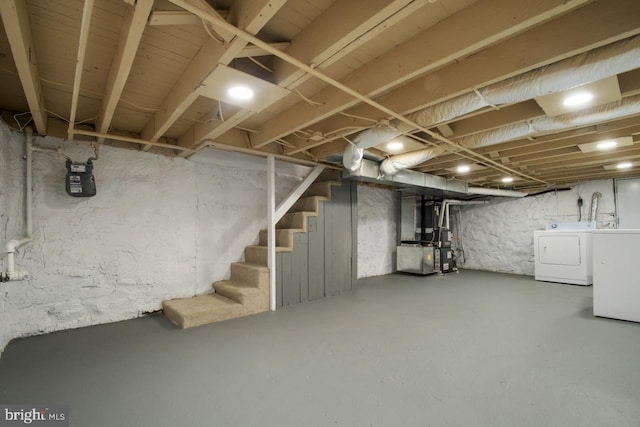 basement featuring heating unit and washer and clothes dryer