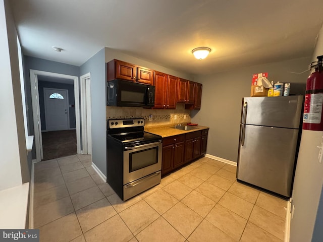 kitchen with sink, light tile patterned floors, backsplash, and appliances with stainless steel finishes