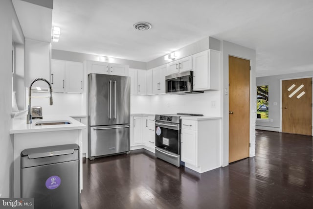 kitchen with decorative backsplash, white cabinets, dark hardwood / wood-style floors, sink, and stainless steel appliances