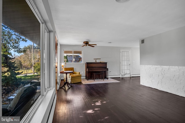 interior space with dark wood-type flooring, ceiling fan, and baseboard heating