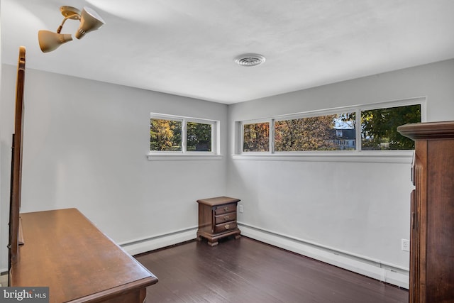 interior space featuring multiple windows, baseboard heating, and dark hardwood / wood-style flooring