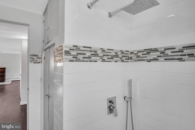 bathroom with a tile shower and wood-type flooring