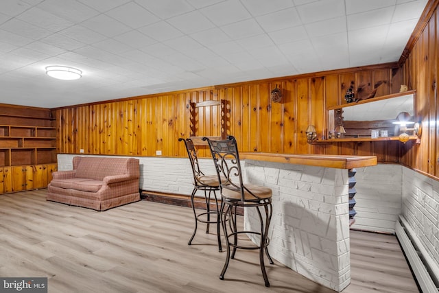 bar with light hardwood / wood-style floors, brick wall, baseboard heating, and wooden walls