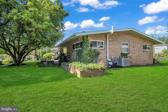 view of side of home with central AC and a yard