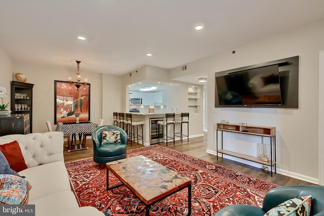 living room featuring hardwood / wood-style flooring, wine cooler, and an inviting chandelier