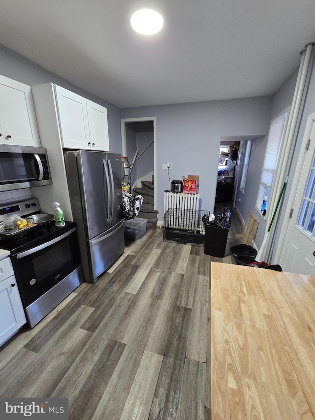 kitchen featuring appliances with stainless steel finishes, white cabinetry, wooden counters, and dark hardwood / wood-style floors