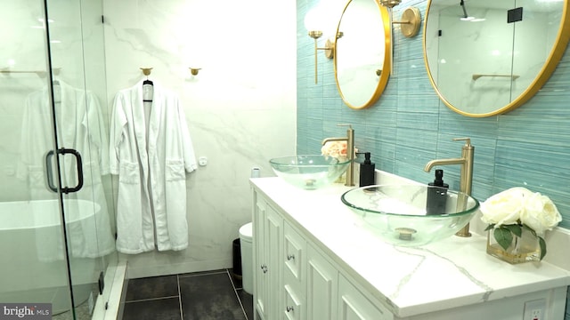 bathroom featuring vanity, a shower with shower door, tile patterned floors, and tile walls