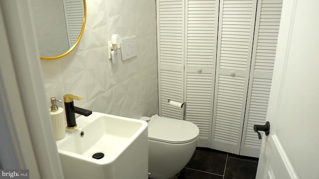 bathroom featuring toilet, tile patterned floors, sink, and tile walls