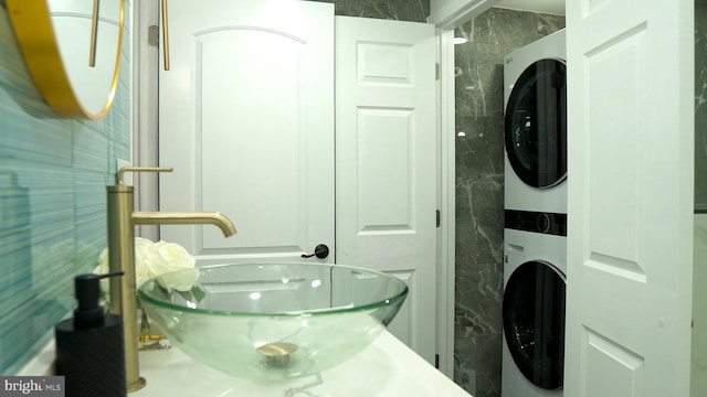 bathroom featuring stacked washer / drying machine and tile walls