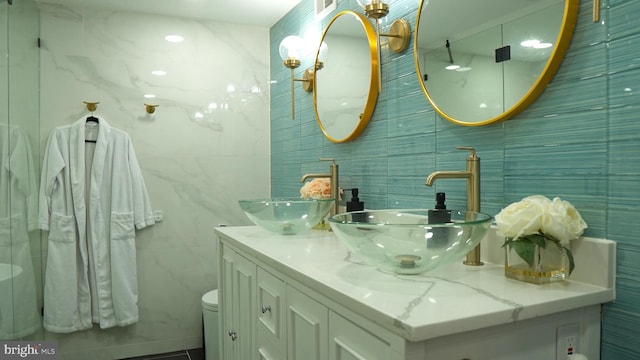 bathroom featuring vanity, toilet, and tile walls