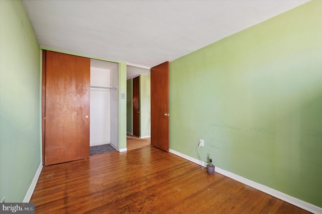 unfurnished bedroom with a closet and dark hardwood / wood-style flooring