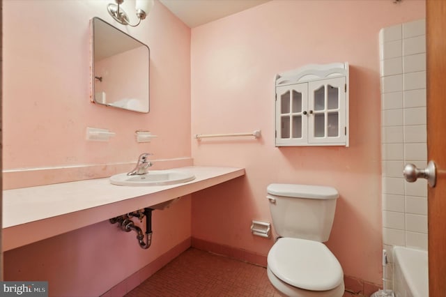 bathroom with a washtub, toilet, and sink