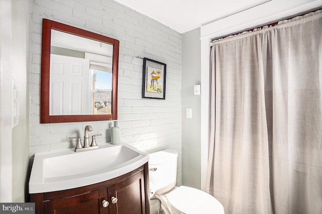 bathroom with brick wall, toilet, and vanity