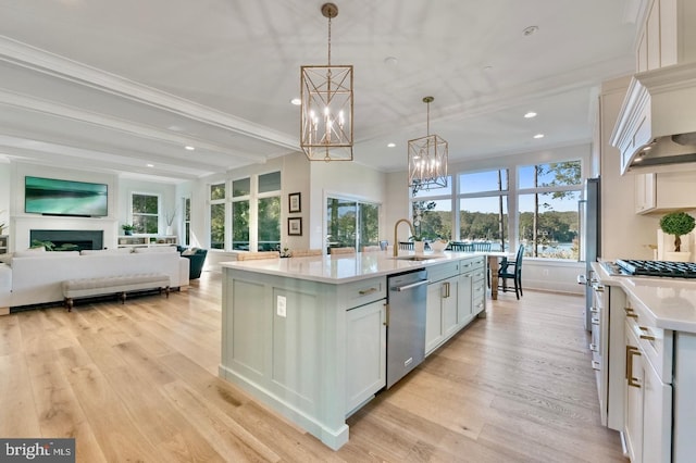 kitchen featuring stainless steel appliances, a kitchen island with sink, pendant lighting, light hardwood / wood-style flooring, and white cabinetry