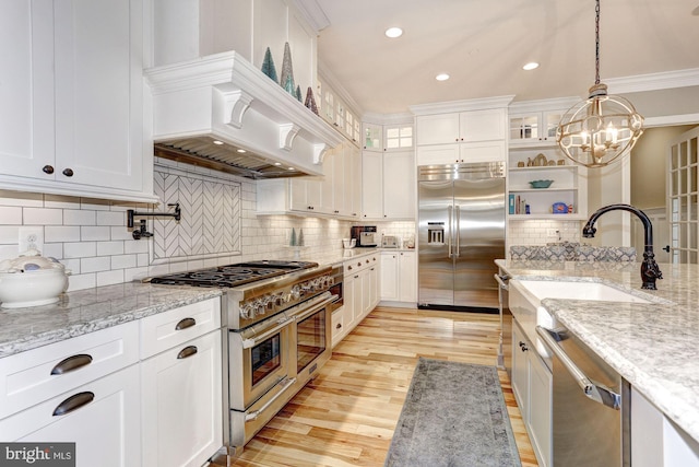 kitchen with white cabinets, high quality appliances, light stone countertops, and ornamental molding