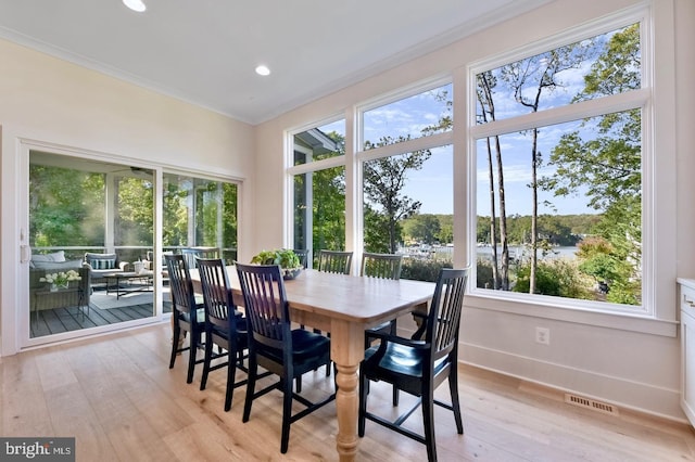 dining area featuring light wood-type flooring and crown molding