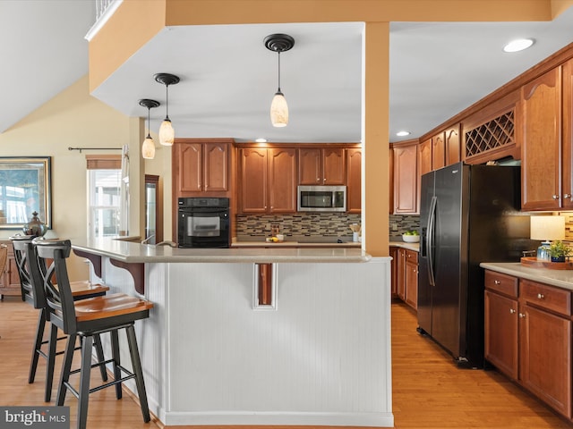 kitchen featuring pendant lighting, stainless steel appliances, a breakfast bar area, and light hardwood / wood-style flooring