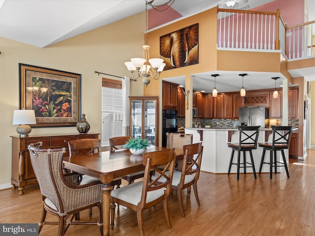 dining space featuring a high ceiling, light hardwood / wood-style flooring, and a notable chandelier