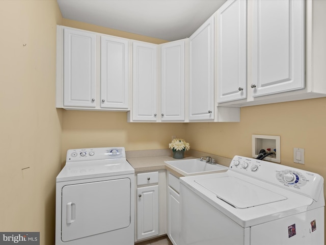 washroom with cabinets, washer and dryer, and sink