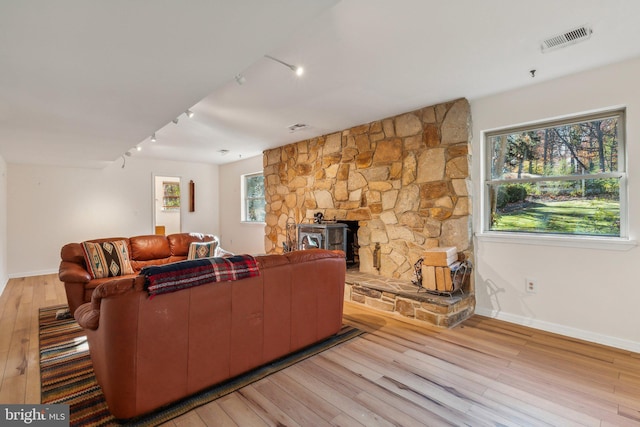 living room featuring a wood stove, light wood-type flooring, and track lighting