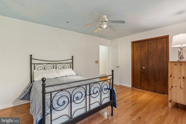 bedroom with light hardwood / wood-style flooring, ceiling fan, and a closet