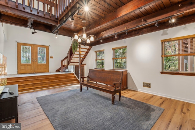 foyer entrance with wooden ceiling, beam ceiling, an inviting chandelier, wood-type flooring, and french doors