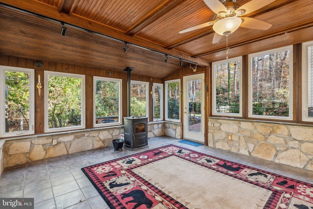 unfurnished sunroom with track lighting, a wood stove, beam ceiling, wooden ceiling, and ceiling fan