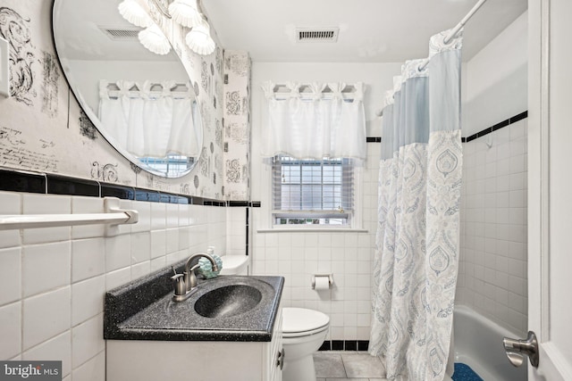 full bathroom featuring tile patterned floors, toilet, vanity, shower / tub combo with curtain, and tile walls