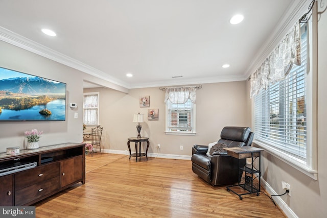 living area featuring light hardwood / wood-style floors, a healthy amount of sunlight, and ornamental molding