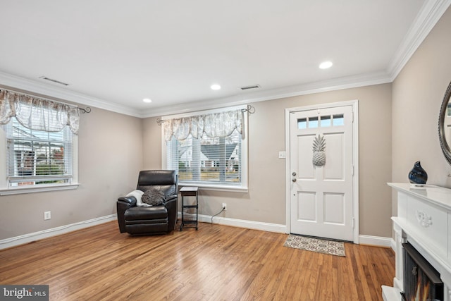 entryway with ornamental molding and light hardwood / wood-style flooring