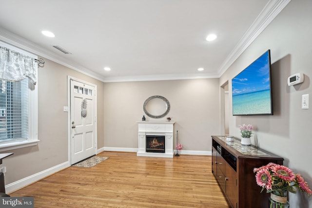 entryway with light hardwood / wood-style floors and crown molding