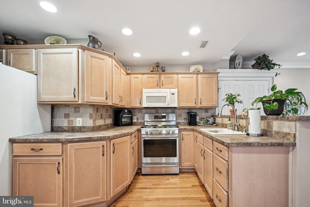 kitchen featuring sink, light hardwood / wood-style floors, stainless steel range with gas cooktop, decorative backsplash, and light brown cabinets