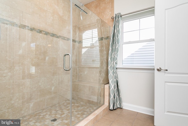 bathroom with a shower with door and tile patterned flooring