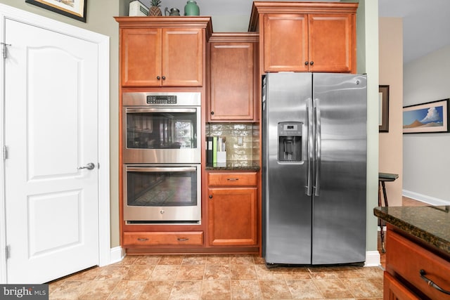 kitchen with decorative backsplash, stainless steel appliances, and dark stone countertops