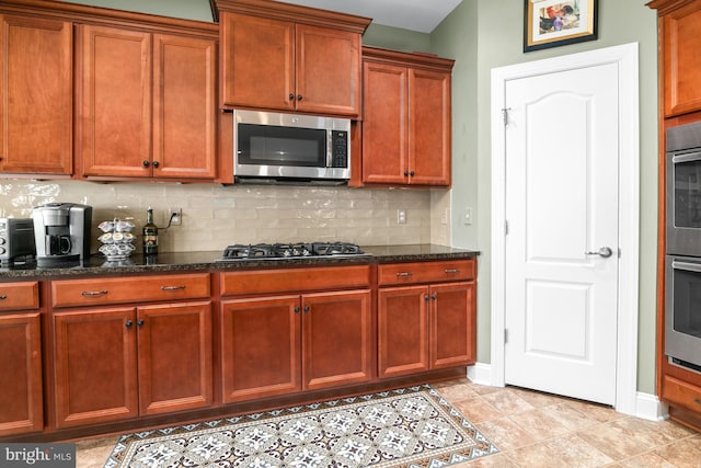 kitchen featuring light tile patterned flooring, tasteful backsplash, stainless steel appliances, and dark stone counters