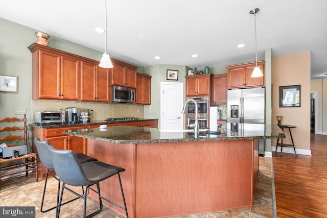 kitchen featuring appliances with stainless steel finishes, pendant lighting, and an island with sink