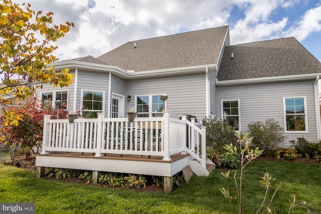 rear view of house featuring a wooden deck and a lawn