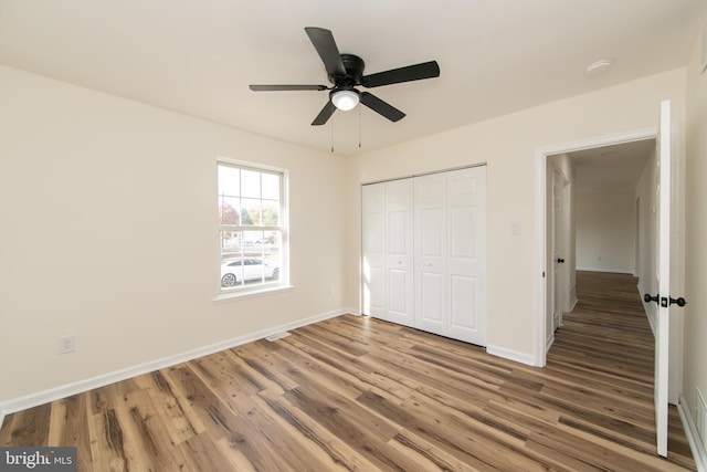 unfurnished bedroom with a closet, wood-type flooring, and ceiling fan