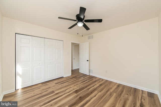 unfurnished bedroom with ceiling fan, a closet, and light wood-type flooring