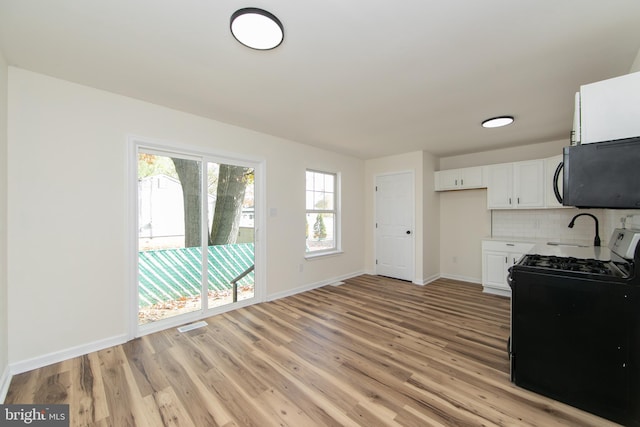 kitchen with sink, black appliances, tasteful backsplash, light hardwood / wood-style flooring, and white cabinets