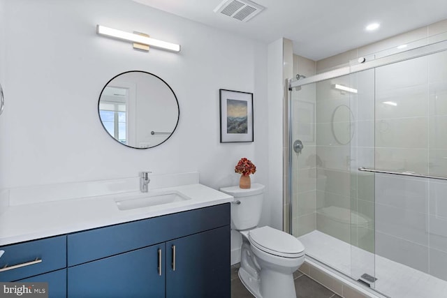 bathroom with a shower with door, vanity, toilet, and tile patterned floors