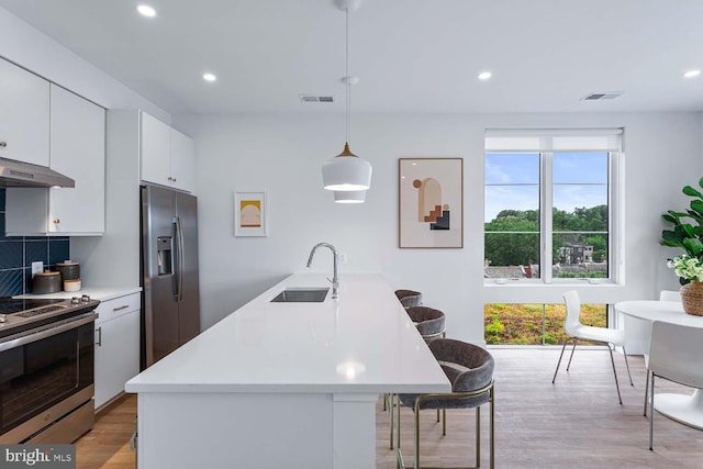 kitchen featuring extractor fan, stainless steel appliances, sink, decorative light fixtures, and white cabinetry