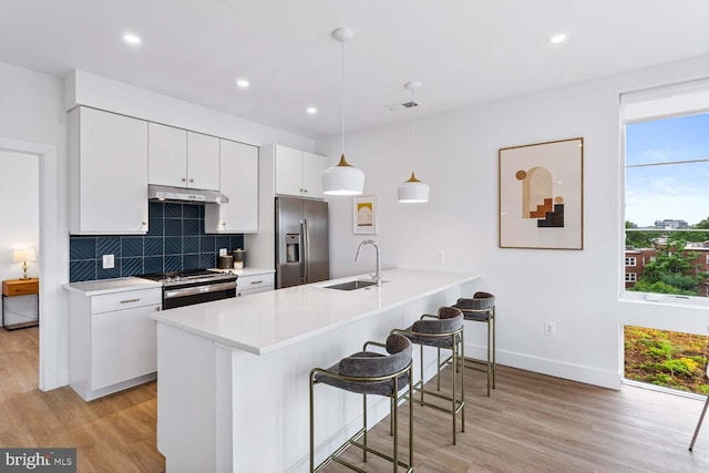 kitchen with light hardwood / wood-style flooring, stainless steel appliances, sink, pendant lighting, and white cabinetry