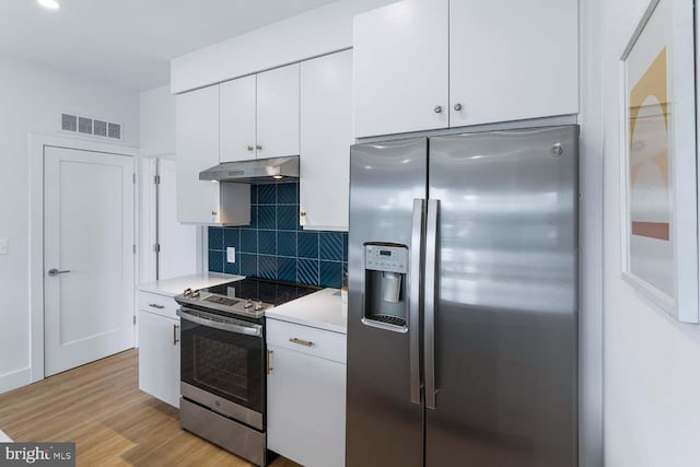 kitchen with backsplash, appliances with stainless steel finishes, light hardwood / wood-style flooring, and white cabinetry