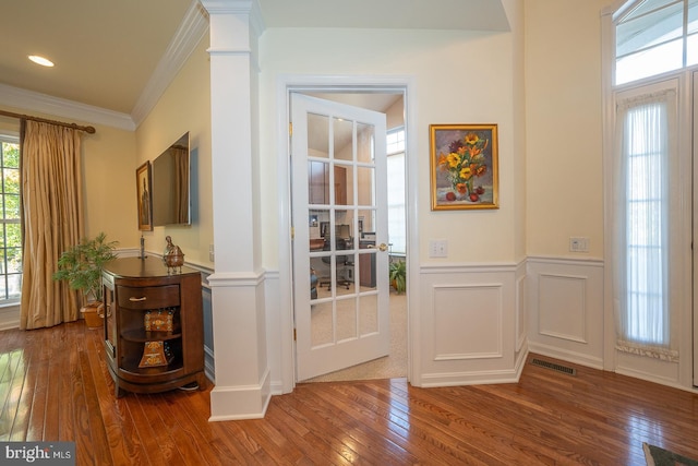 entryway featuring decorative columns, hardwood / wood-style flooring, and ornamental molding