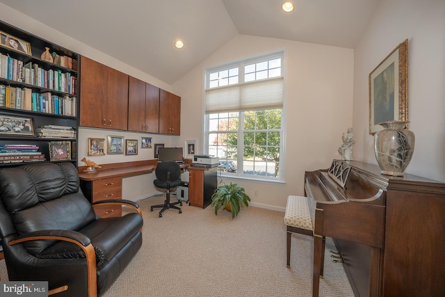 carpeted office space with built in desk and lofted ceiling