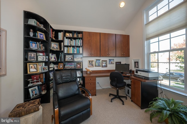 office featuring built in desk, light carpet, and vaulted ceiling