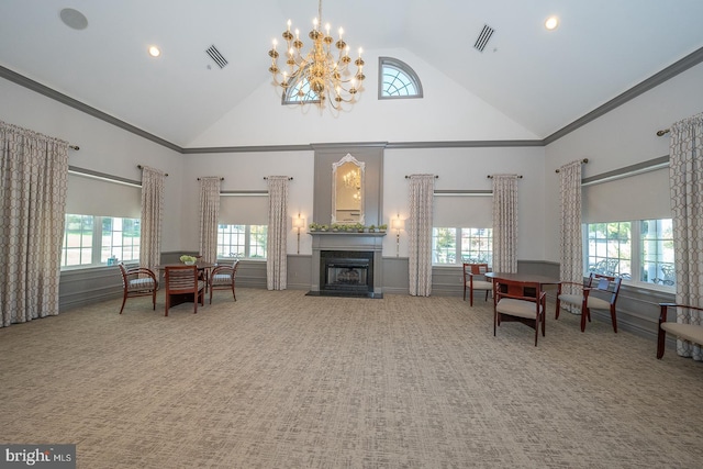 carpeted living room with a chandelier, high vaulted ceiling, and a healthy amount of sunlight